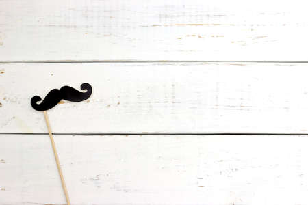 Paper heart shape fake mustaches in sticks in front of wooden white background. Happy fathers day concept.の写真素材