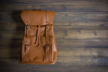 Brown leather bag on wooden table. Top view. Travel concept.の写真素材