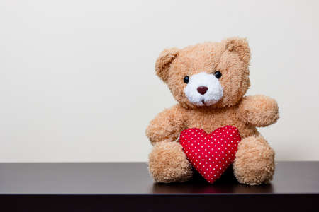 bear doll and red heart on wooden tableの写真素材