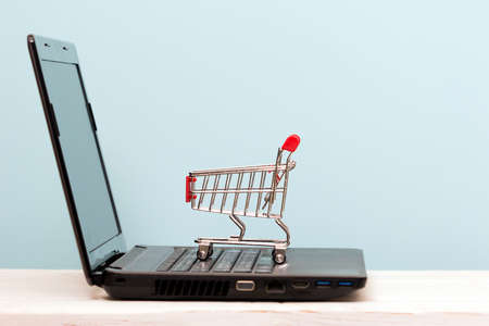 Small shopping cart on Laptop for shopping online with blue background, Technology business online concept.の写真素材