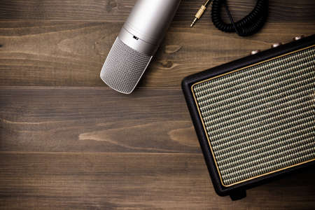 Guitar amplifier and microphone on wooden background. Vintage effect style.