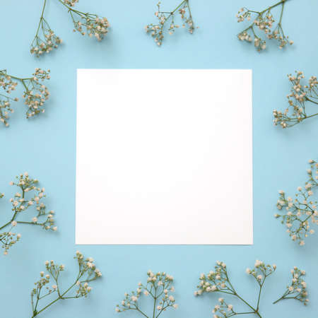 Creative layout made of flowers with paper card note on blue background. Flat lay. Nature conceptの写真素材