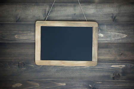 Empty chalkboard on the rope attached to shabby white wooden backgroundの写真素材