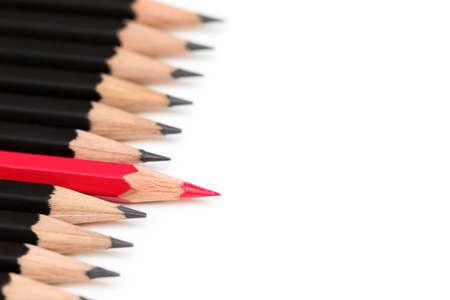 Red pencil standing out from crowd of plenty identical black fellows on white table. Leadership, uniqueness, independence, initiative, strategy, dissent, think different, business success concept.の写真素材