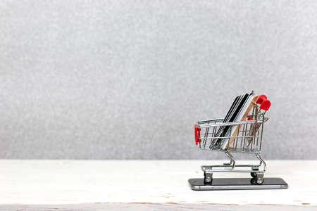 Online shopping concept. Mobile phone or smartphone with cart and credit cards.
