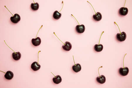 Pattern of dark cherry on pink background top view. Flat lay. Minimal style.