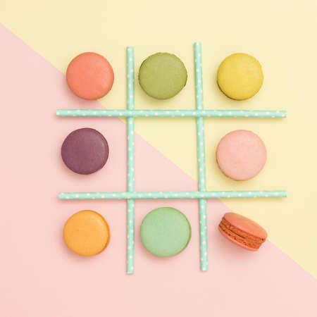 Tick-tack-toe made of macaroons and straws on pastel background. Flat lay. Healthy food concept.