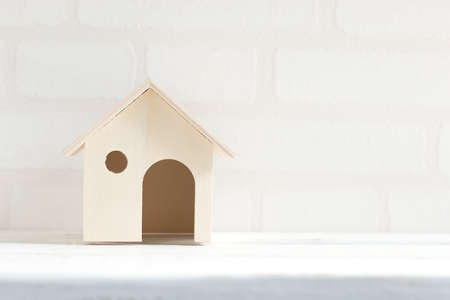 Model of the house on white wooden table brick wallpaper background. Home business concept.の写真素材