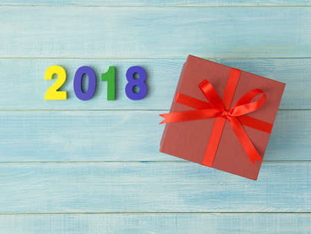 New Year 2018 is coming concept. Colorful wooden number 2018 and red gift box on blue table with...
