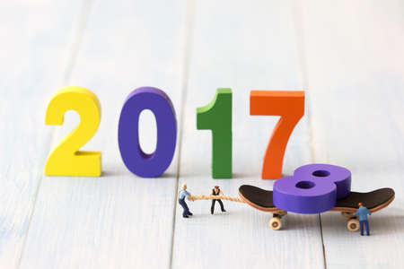 Group of miniature people assembling colorful wooden number 2018 replace 2017. Team support and help concept. Business teamwork concept. New year holiday concept.の写真素材