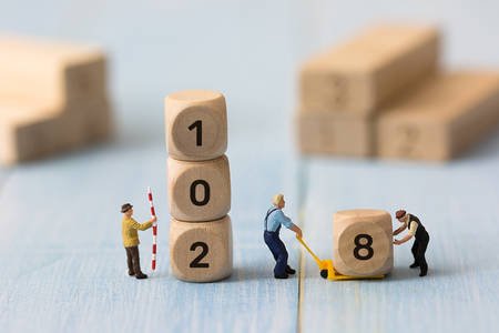 Group of miniature people assembling wooden cube number 2018. Team support and help concept....