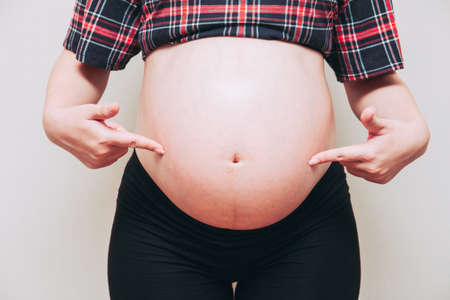 Pregnant woman pointing at her belly. A mother waiting for the baby.の写真素材