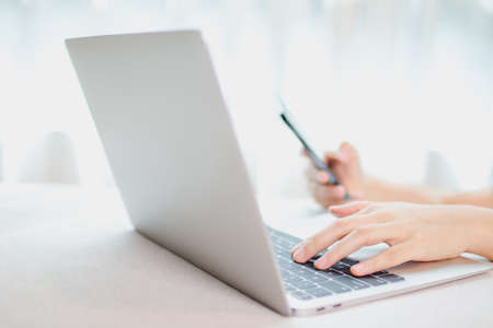 Online payment concept. Hand holding a smartphone and using laptop for online shopping.の写真素材