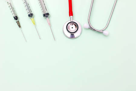 Red stethoscope for cardiac on green background with syringe.Equipment of physician for diagnose heartbeat in hospitality.Health care and physical examination conceptの写真素材