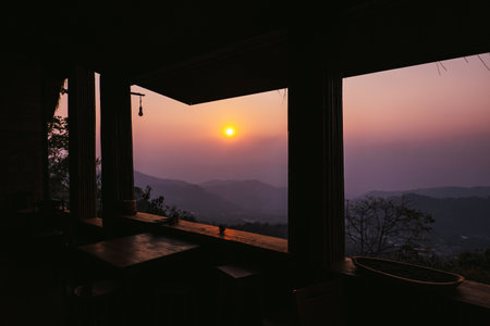 View through window of beautiful sunset sky over forest and mountainの写真素材