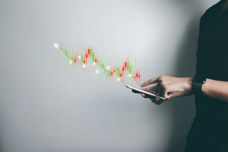 Investor is trading stock with smartphone, trader analyze stock price with candlestick chart, business growth, currency exchange, economic progress, finance with internet technology.の写真素材