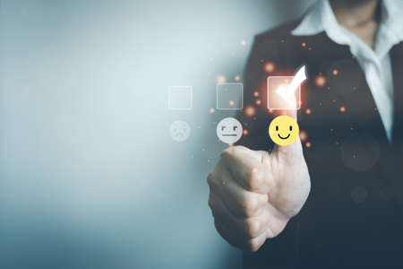 Customer satisfaction concept, businesswoman thumb up rating on smile face icon, giving the highest score, very happy and satisfied with excellent service, feedback from guest.の写真素材