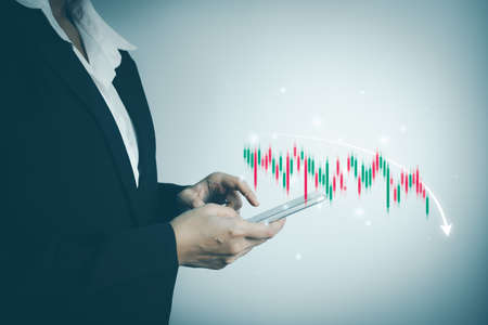 Investor analyze stock chart by smartphone,Businesswoman forecast graph in Bearish downtrend,Inflation Effect,Economic Depression, War effect Russia and Ukraine, trade war finance, covid-19 impactの写真素材