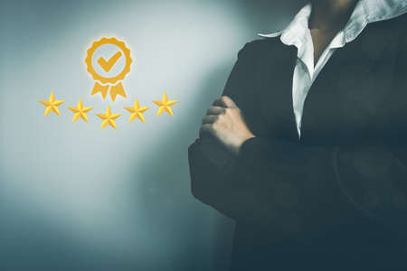Businesswoman showing the symbol of top service 5 star quality assurance, excellent warranty, world standard, ISO certification, development and improve the quality of the organization concept.の写真素材