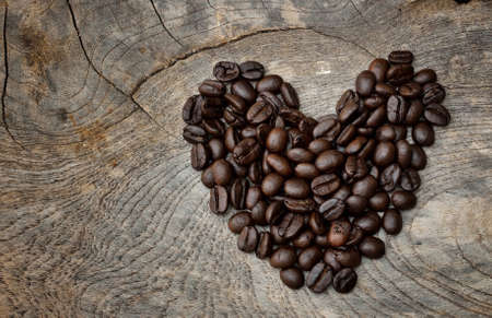 Heart shape made from coffee beans on wooden surface.の写真素材