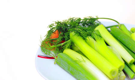 sliced green onions and dill close-up. On the plate are onions and the bunch of greens in the backgroundの写真素材