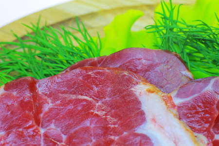 On a wooden board is smoked bacon with vegetables. Tomato, cucumber, salad, sliced bacon are...