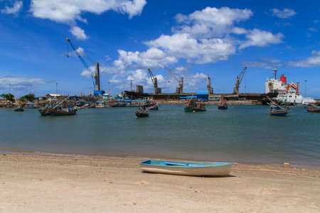 Fishing boat parking at industry cranes and cargo on portの写真素材