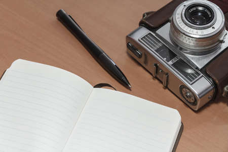 Old retro camera and note book on wooden boards abstract background.の写真素材