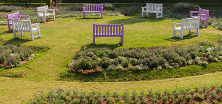 Benches arrange a circle in the outdoor garden among the many colorful plants.の写真素材