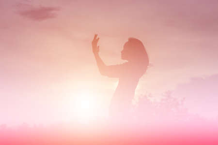 Silhouette of woman praying over beautiful sky backgroundの写真素材