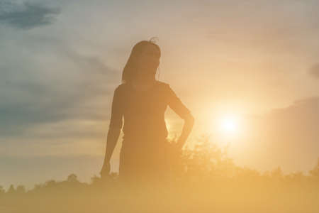 Silhouette of woman praying over beautiful sky backgroundの写真素材
