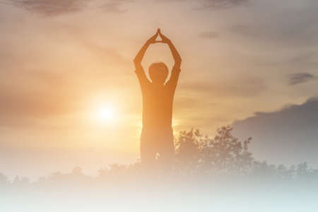 Silhouette of woman praying over beautiful sky backgroundの写真素材