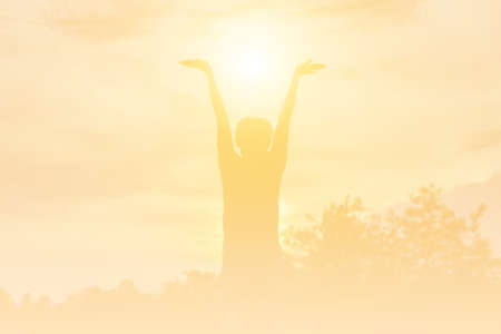 Silhouette of woman praying over beautiful sky background