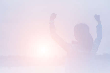 Silhouette of woman praying over beautiful sky backgroundの写真素材