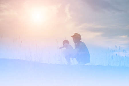 Silhouette of Mother and Baby Daughter Running and Dancing at Sunsetの写真素材