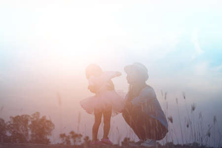 Silhouette of Mother and Baby Daughter Running and Dancing at Sunsetの素材 [FY31086961054]