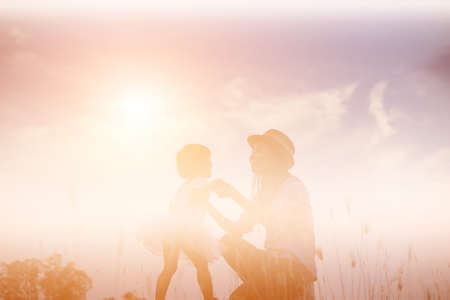 Silhouette of Mother and Baby Daughter Running and Dancing at Sunset