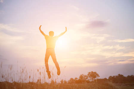 An adult man jumping in joyous at the coastline during sunsetの写真素材