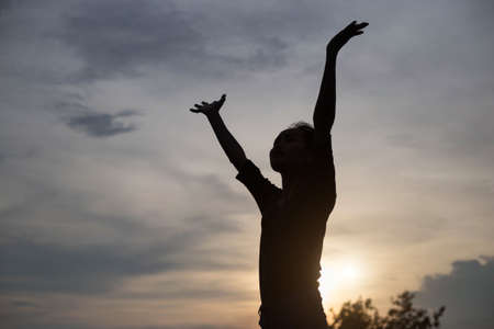 A joyful adult woman looking at the coastline during sunsetの写真素材
