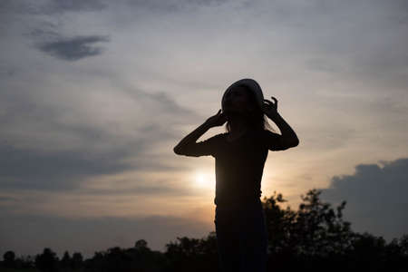 A joyful adult woman looking at the coastline during sunsetの写真素材