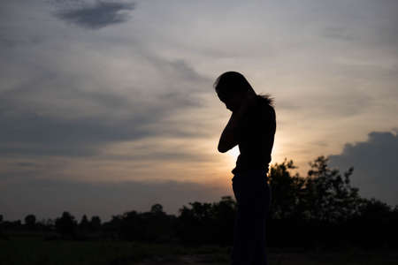 A sad adult woman looking at the coastline during sunsetの写真素材