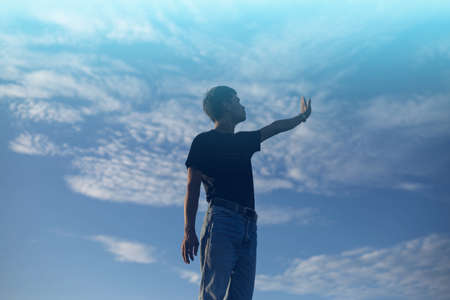 An adult man raising his arms at the coastlineの写真素材