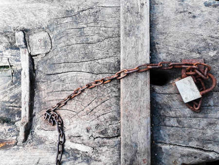 The padlock was attached to an old chain resting on an old wooden floor.の写真素材
