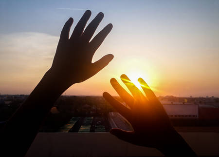 Beautiful sunset, silhouette touch the sun, image of finger catch the sun and evening sky, Silhouette Hands catching the falling sun during sunset.の写真素材