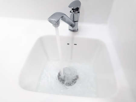 basin, wash basin close-up, basin and tap flowing , white wash basin close up, Detail of the basin, Bathroom sign toilet, working water tap, water flowing from the tap in the sink close-up, Water tap flowingの写真素材