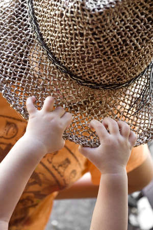 photo of a baby's hand grabbing a girl's hat - achievementの写真素材
