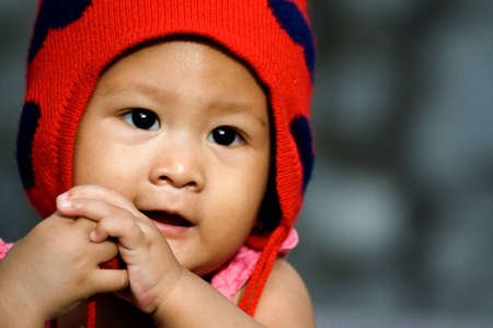 portrait of a cute asian baby girl with a red hat seems to enjoy herselfの写真素材
