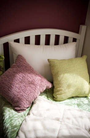 single white bed with colorful pillows near the window - relaxation