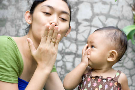 beautiful asian young mother teaching her sweet baby girl a goodbye kiss - early learningの写真素材