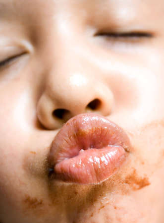 funny expression of an asian little girl imitating a kiss action. shallow depth of field. focusing on the smeared lips.の写真素材